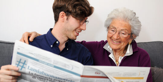 Giovane e donna anziana leggono insieme il giornale