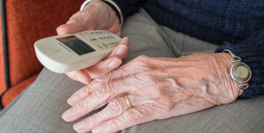 Persona anziana seduta con telefono in mano